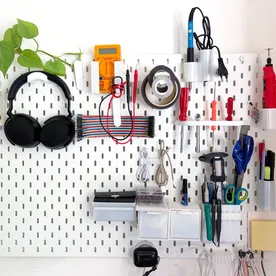 White 3D-printed Skadis attachments organizing tools on a pegboard.